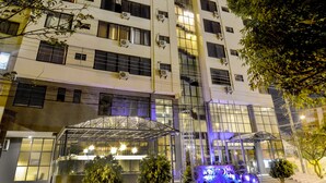 A multi-story hotel with a glass facade, outdoor seating area, and a well-lit entrance. - Gran Hotel Toloma (Cochabamba)