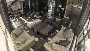 A spacious lobby with a modern design, featuring a central seating area with sofas and a coffee table, a staircase, and a reception desk. - Gran Hotel Toloma (Cochabamba)