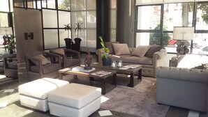 A modern living room with a beige sofa, two armchairs, a coffee table, and a white ottoman. - Gran Hotel Toloma (Cochabamba)