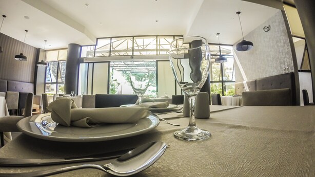 A modern dining area with a high ceiling, large windows, and contemporary furniture. - Gran Hotel Toloma (Cochabamba)