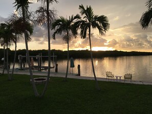 A lakeside view with palm trees, a dock, and a gazebo.