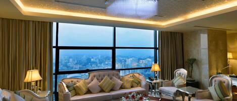 A luxurious hotel room with a large window offering a city view, a plush sofa, elegant chairs, and a chandelier.