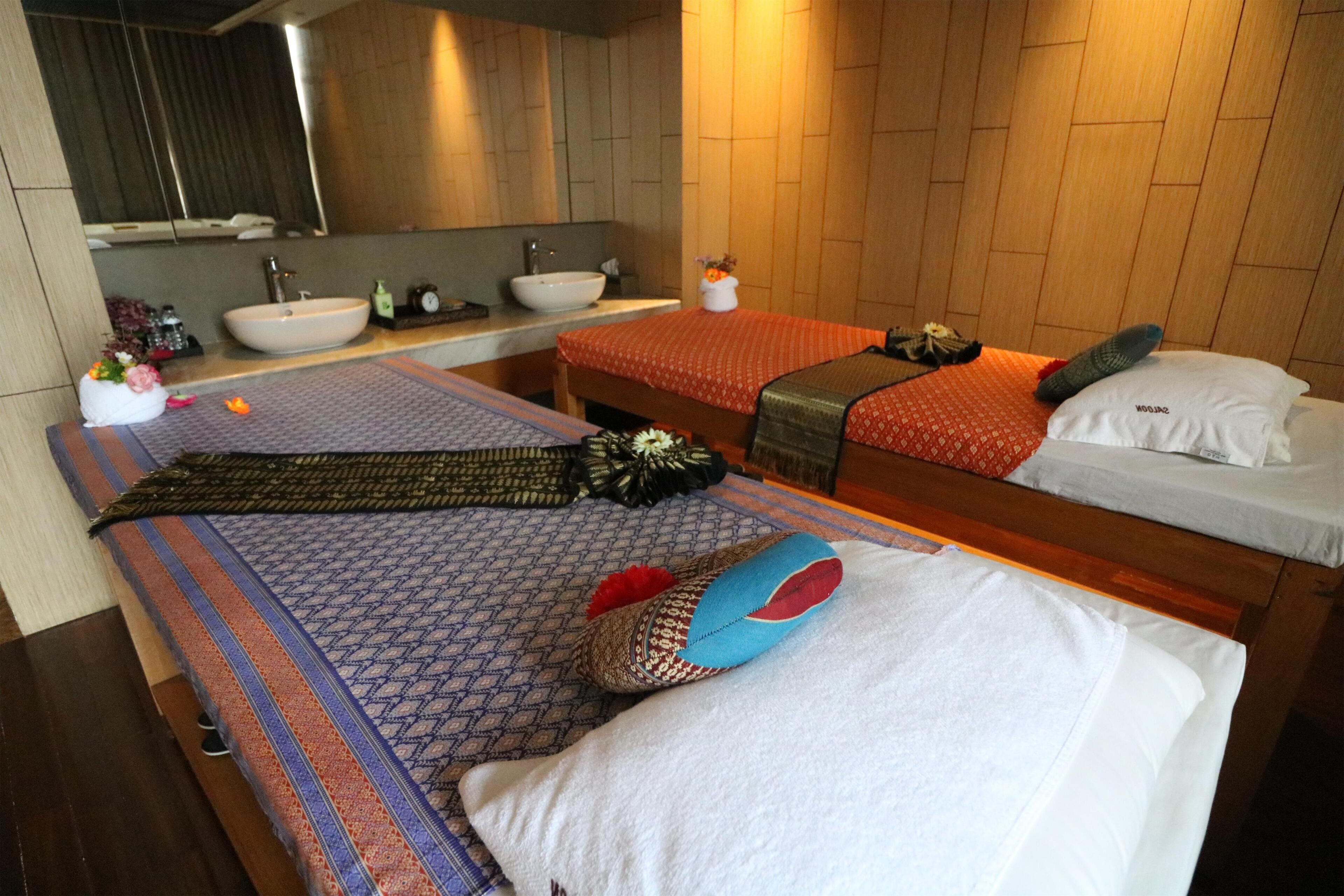 A hotel room with two beds, a large mirror, a sink, and a wooden wall.