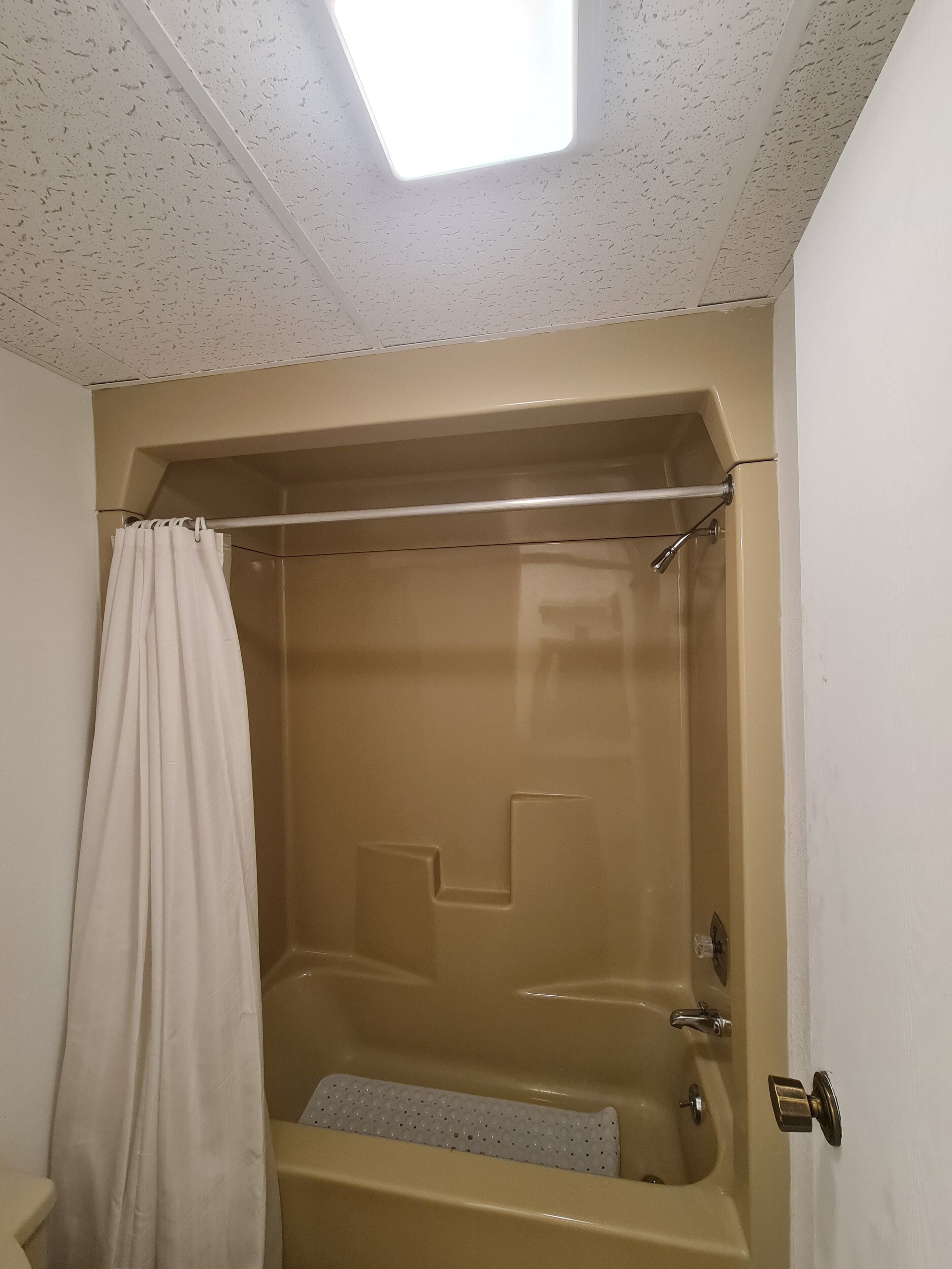 A bathroom with a bathtub, a shower, and a skylight.