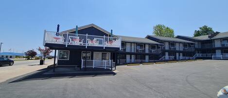A motel with a two-story structure, a covered outdoor seating area, and a parking lot.