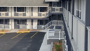 A multi-story motel with a parking lot and a small garden area. - Bayside Inn  (St Ignace)