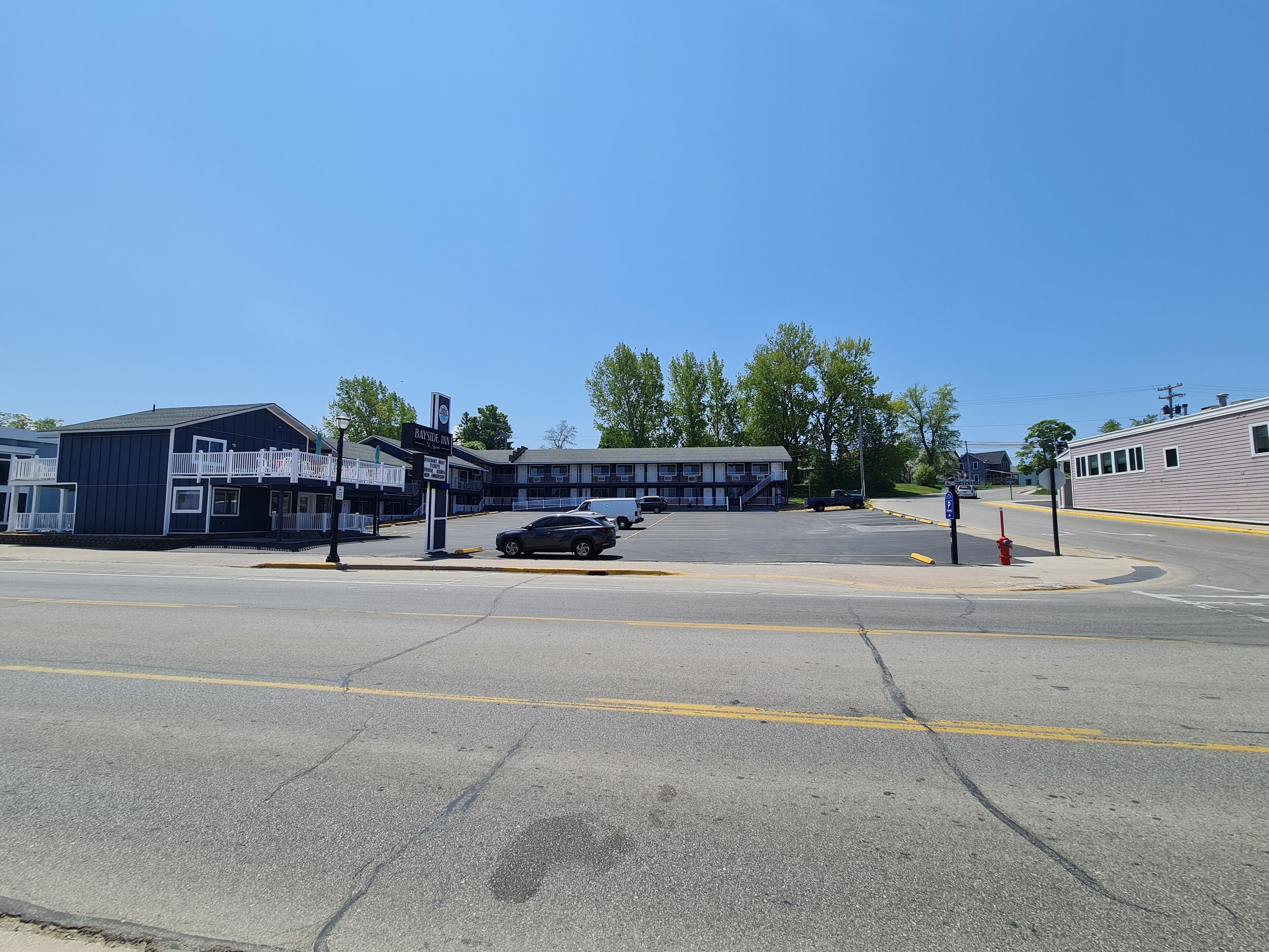 A motel with a two-story building, a parking lot, and a street intersection.