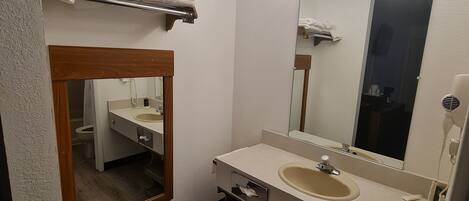 A bathroom with a wooden vanity, a sink, a mirror, and a towel rack.