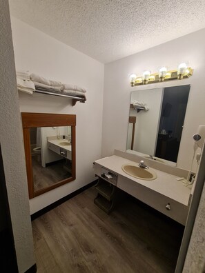 A bathroom with a wooden vanity, a sink, a mirror, and a towel rack.