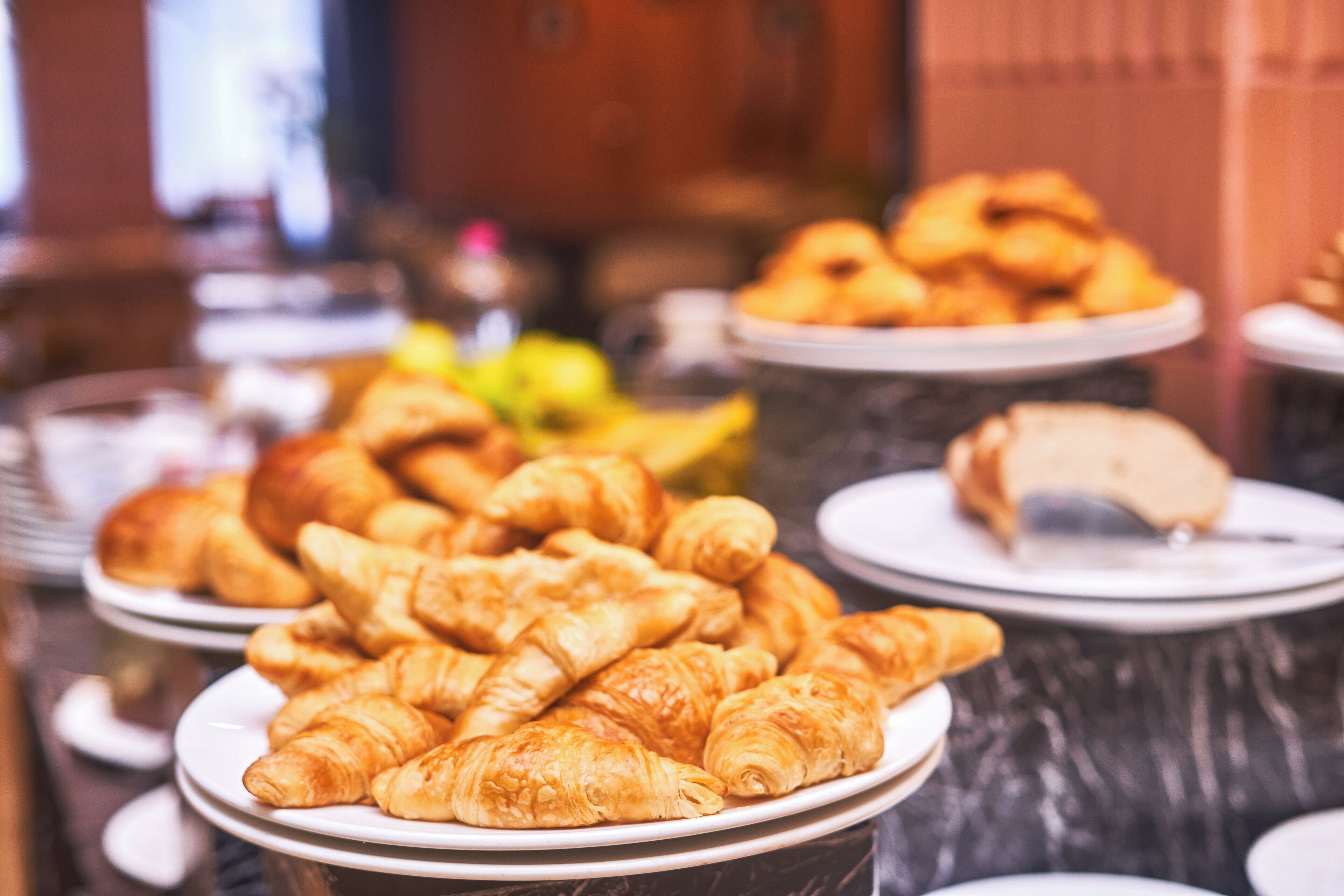 A buffet table with various pastries and a plate of croissants.