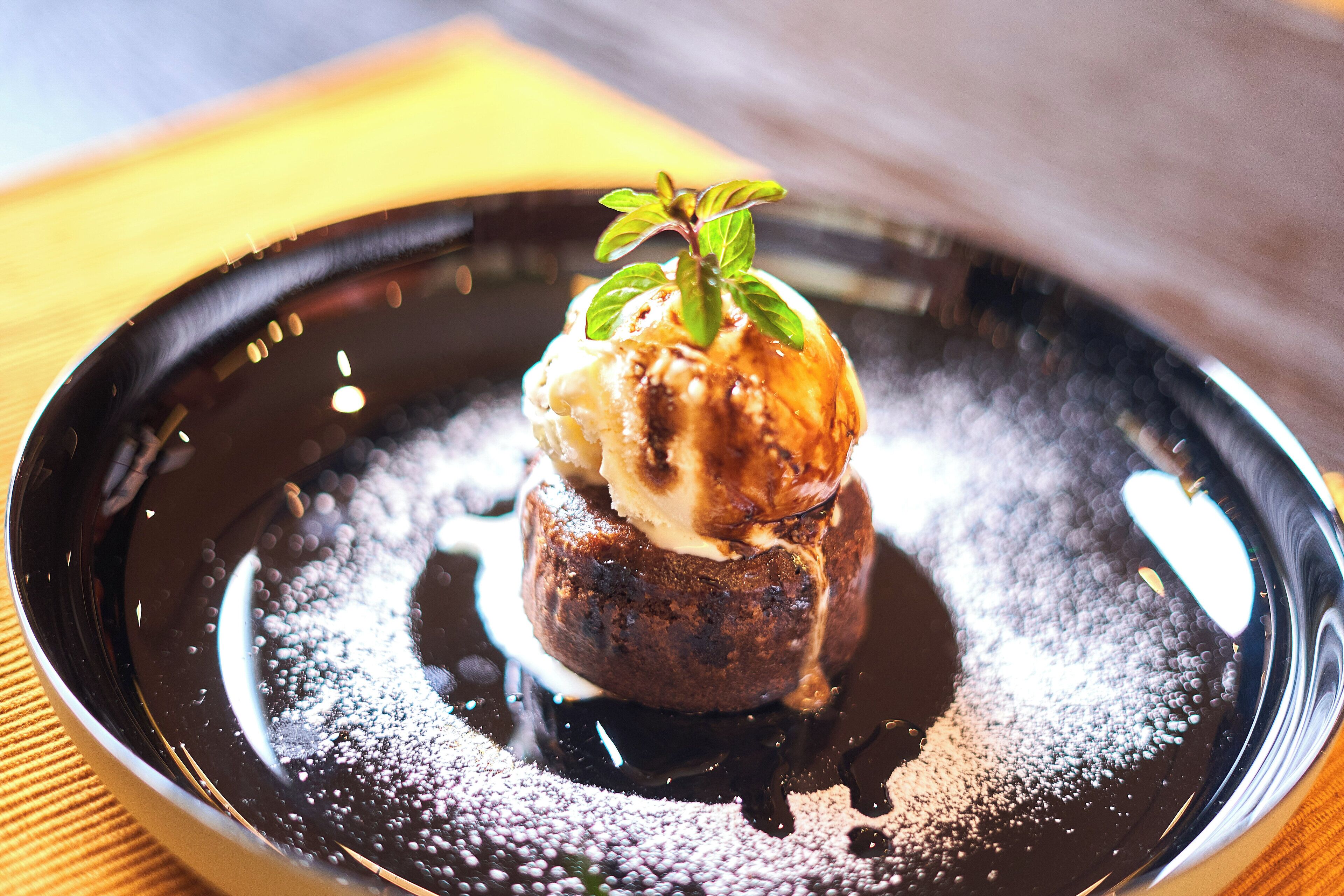 Postre sobre un plat negre amb una branca de menta a sobre.
