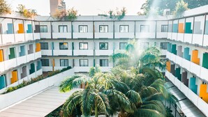 Un edificio de varios pisos con jardín en la azotea, mobiliario exterior y una variedad de plantas.