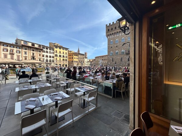 An outdoor dining area with tables and chairs, surrounded by historic buildings. - La Torre Dei Salterelli (Florence)