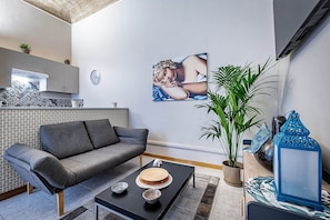 Departamento superior, 1 cama Queen size y sofá cama | Área de sala de estar | Televisión de pantalla plana de 55 pulgadas con canales vía satélite