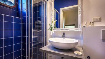 A bathroom with a white sink, a mirror with an ornate frame, and blue-tiled walls.