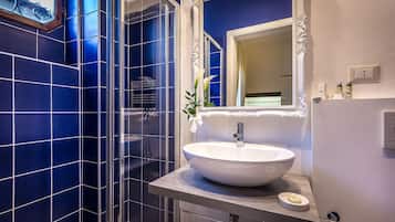 A bathroom with blue tiles, a white sink, and a mirror.