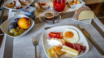 Una mesa de desayuno con platos de huevos, tocino, queso y fruta.