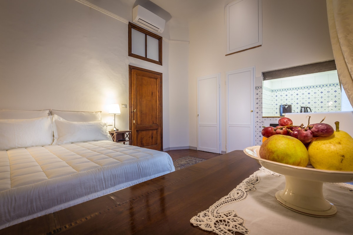 Une chambre à coucher avec un lit, une porte en bois et un panier de fruits posé sur une table.