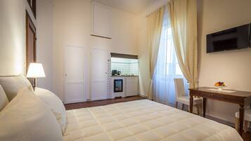 Ein Hotelzimmer mit einem großen Bett, einem Schreibtisch, einem Fernseher und einer Küchenzeile.