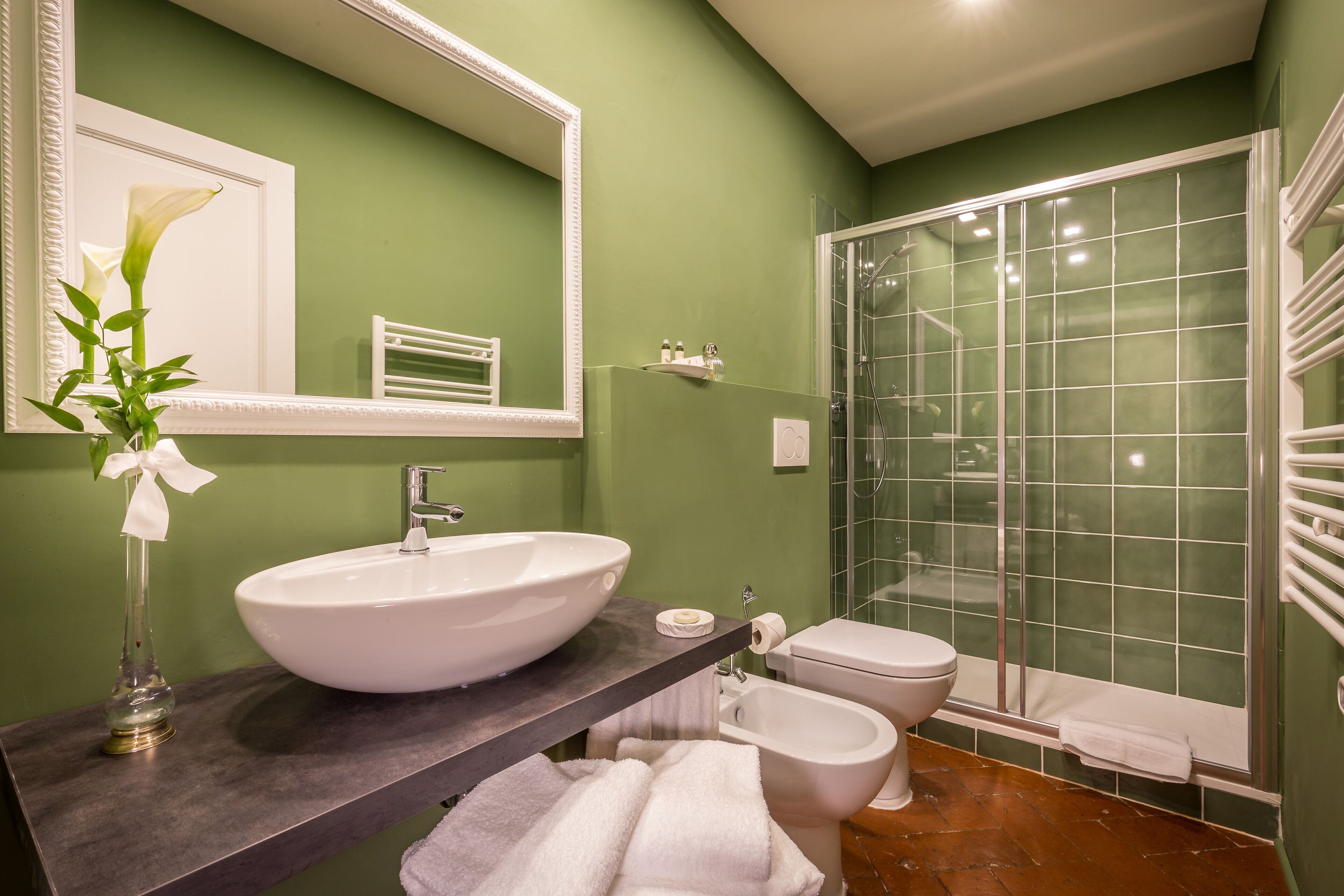A bathroom with a large white sink, a mirror, a toilet, and a glass-enclosed shower.