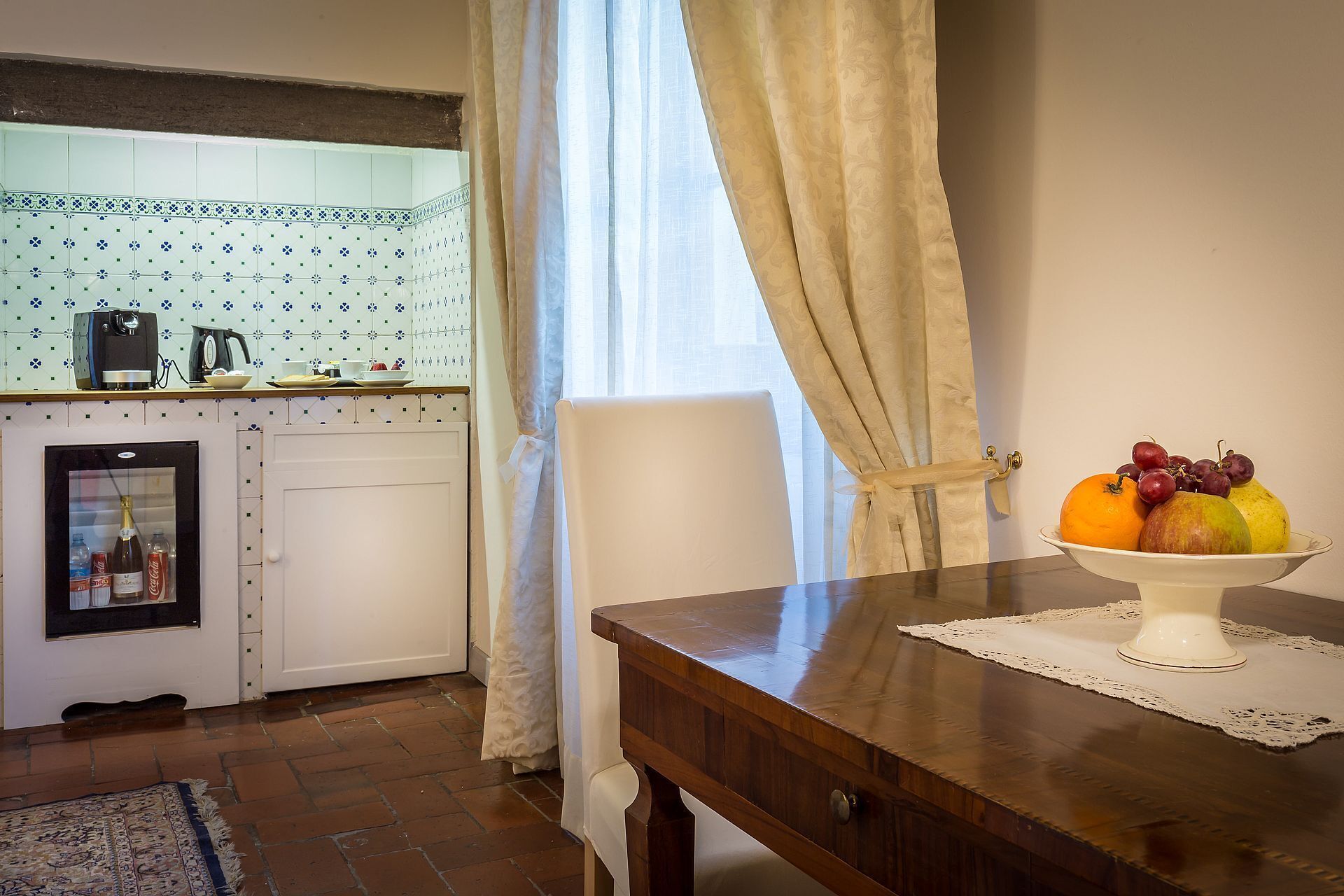 Una cucina con un frigorifero, una macchina da caffè e una ciotola di frutta sul piano di lavoro.