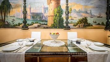 A dining table set with white tablecloths, a fruit bowl, and glassware.