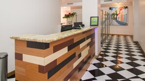 A reception desk with a check-in counter, a computer, and a vase with flowers. - My Hotel in Puerto Rico (San Juan)