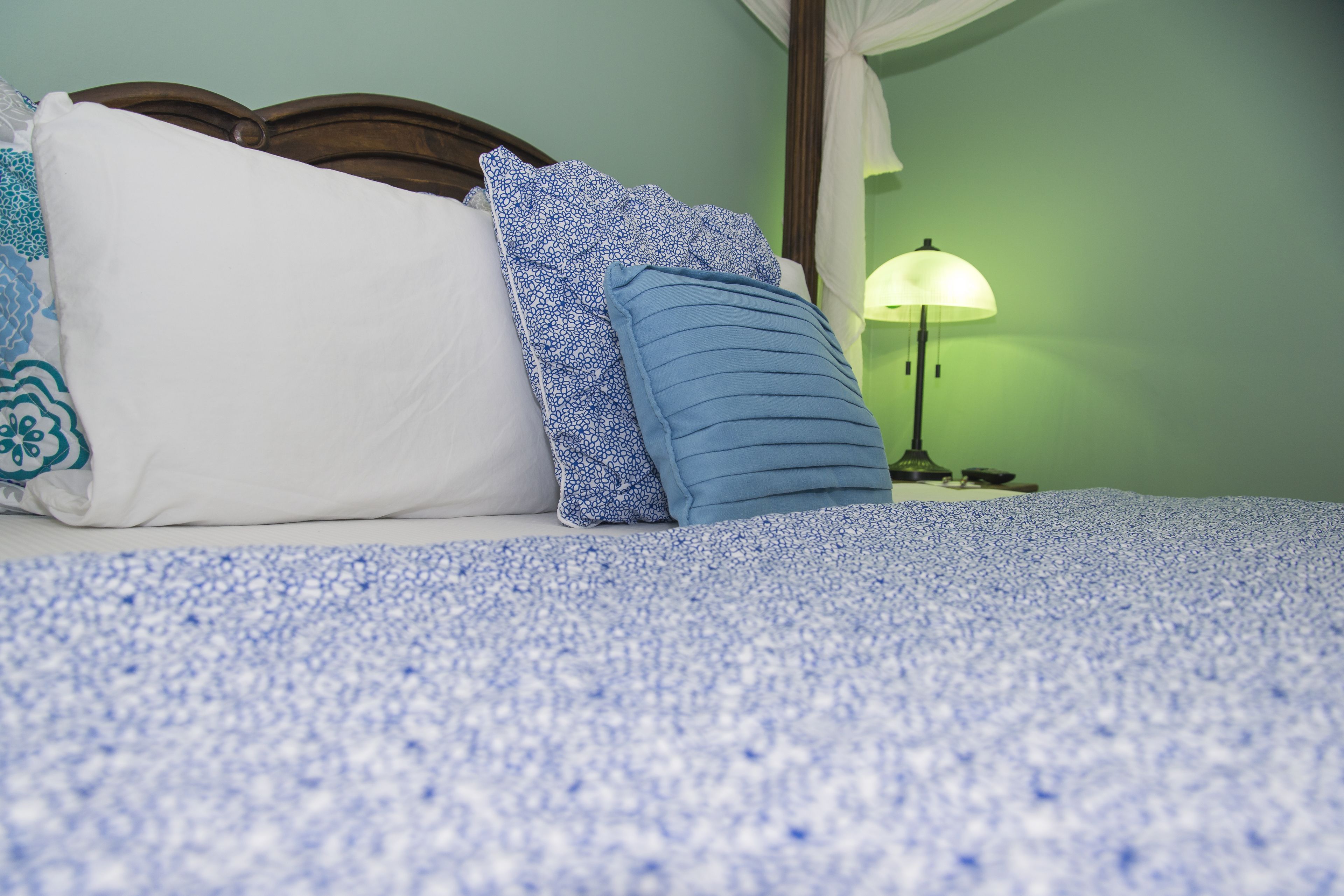 Un lit avec une couvre-lit à motifs bleus et blancs, un oreiller blanc et un oreiller bleu à bord festonné.