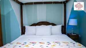 A neatly made bed with white linens and a floral bedspread, a wooden headboard, and a bedside table with a lamp. - My Hotel in Puerto Rico (San Juan)