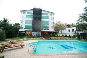 A modern building with a swimming pool, lounge chairs, and a well-maintained garden. - Hotel M (Yangon)