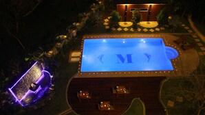 Vista aérea de um hotel com piscina, área de estar externa e entrada bem iluminada.