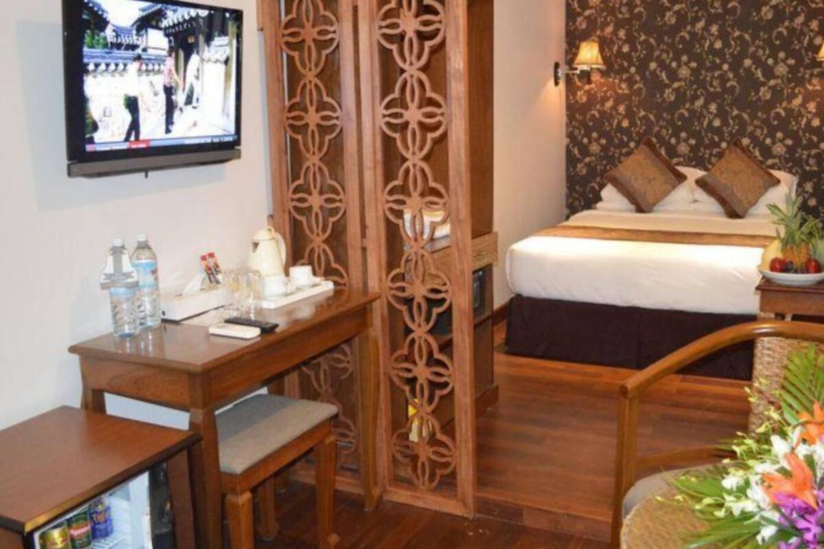 Une chambre d’hôtel comprenant un lit, un bureau, une télévision et un paravent décoratif.