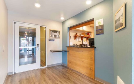 A reception area with a wooden counter, a glass door entrance, and a framed picture on the wall.