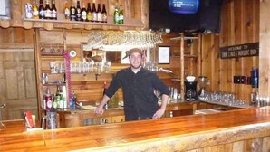 Una zona de bar con estanterías de madera llenas de botellas y vasos, una cafetera y un cartel de bienvenida al Nordic Inn.
