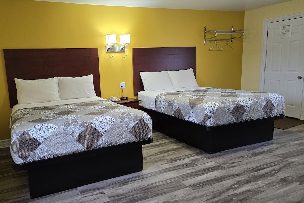 Two single beds with headboards, a nightstand, a wall-mounted lamp, and a door with a sign.