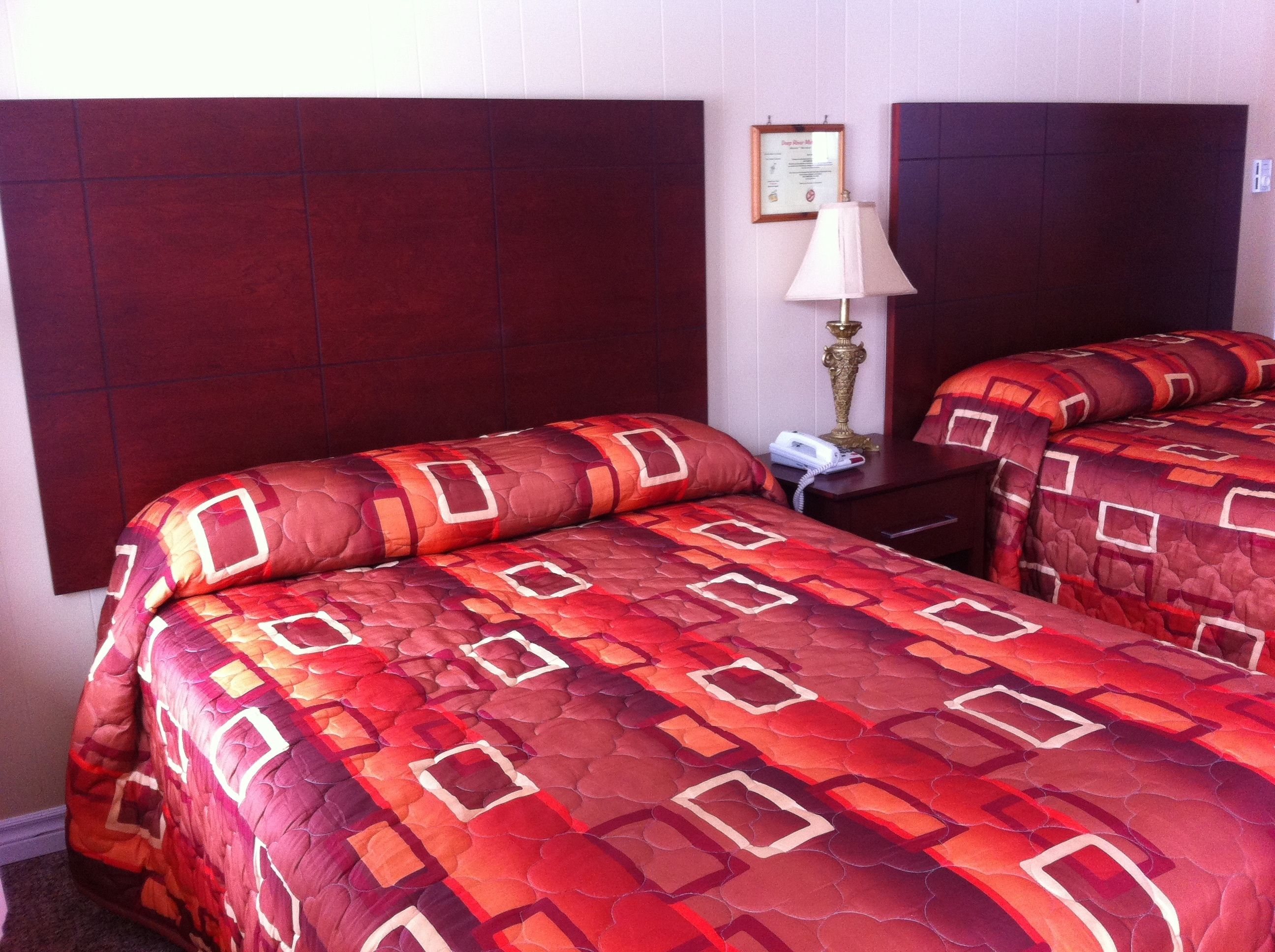 Habitación de hotel con dos camas, una mesita de noche, una lámpara y un menú enmarcado en la pared.