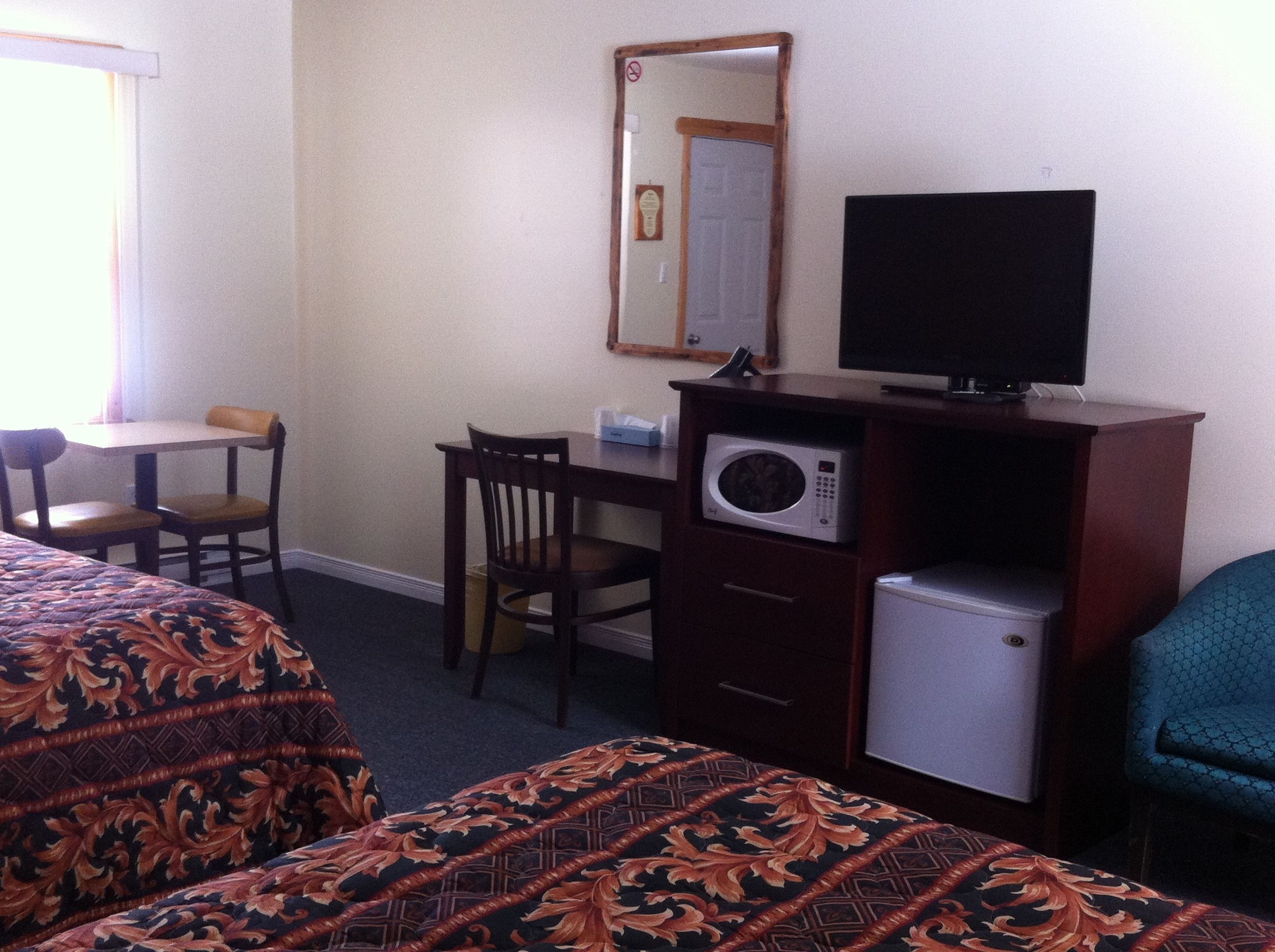 Een hotelkamer met twee bedden, een bureau met stoel, een magnetron, een televisie en een kleine koelkast.