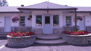 A building with a porch, stone steps, and hanging flower baskets.