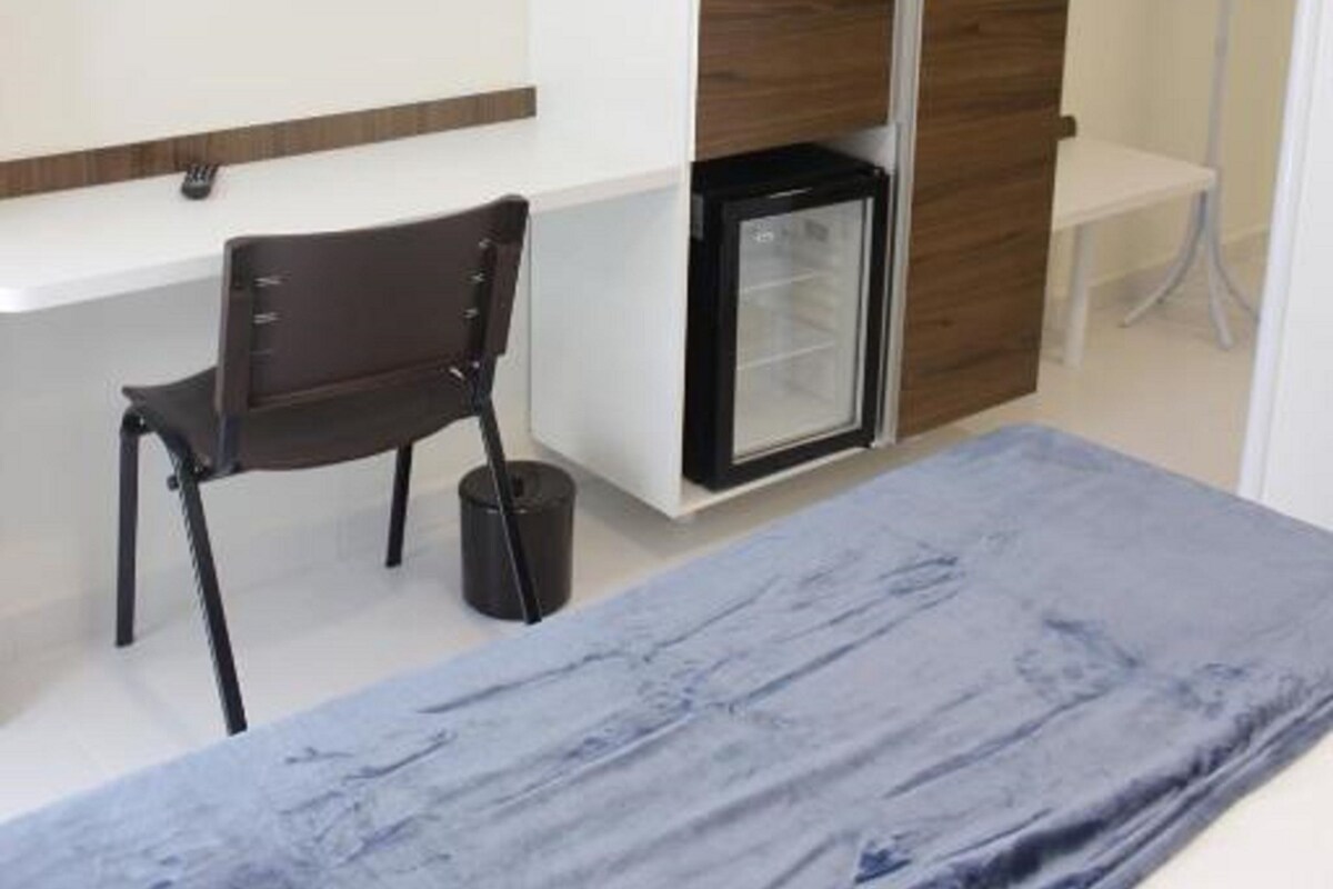 A hotel room with a bed, a desk, a television, and a minibar.