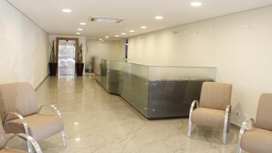 A reception area with a glass counter, two beige chairs, and a marble floor. - Floresta Hotel - Expo Anhembi (São Paulo)