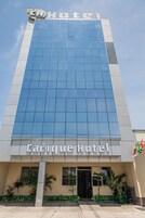 Un hotel con fachada moderna de vidrio y un letrero que dice "Carique Hotel".