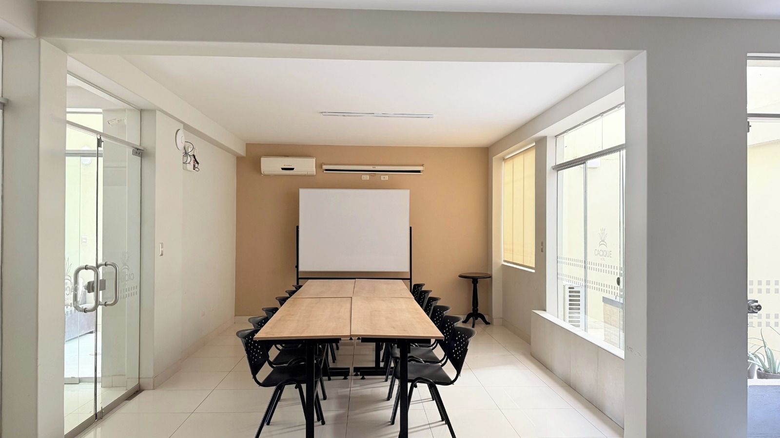 Een vergaderruimte met een lange tafel, stoelen, een whiteboard en een raam met uitzicht.