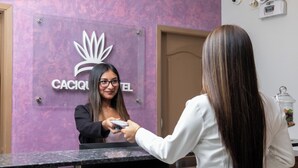 A reception area with a purple wall and a sign that reads "CACIQ HOTEL". - El Cacique Hotel (Piura)