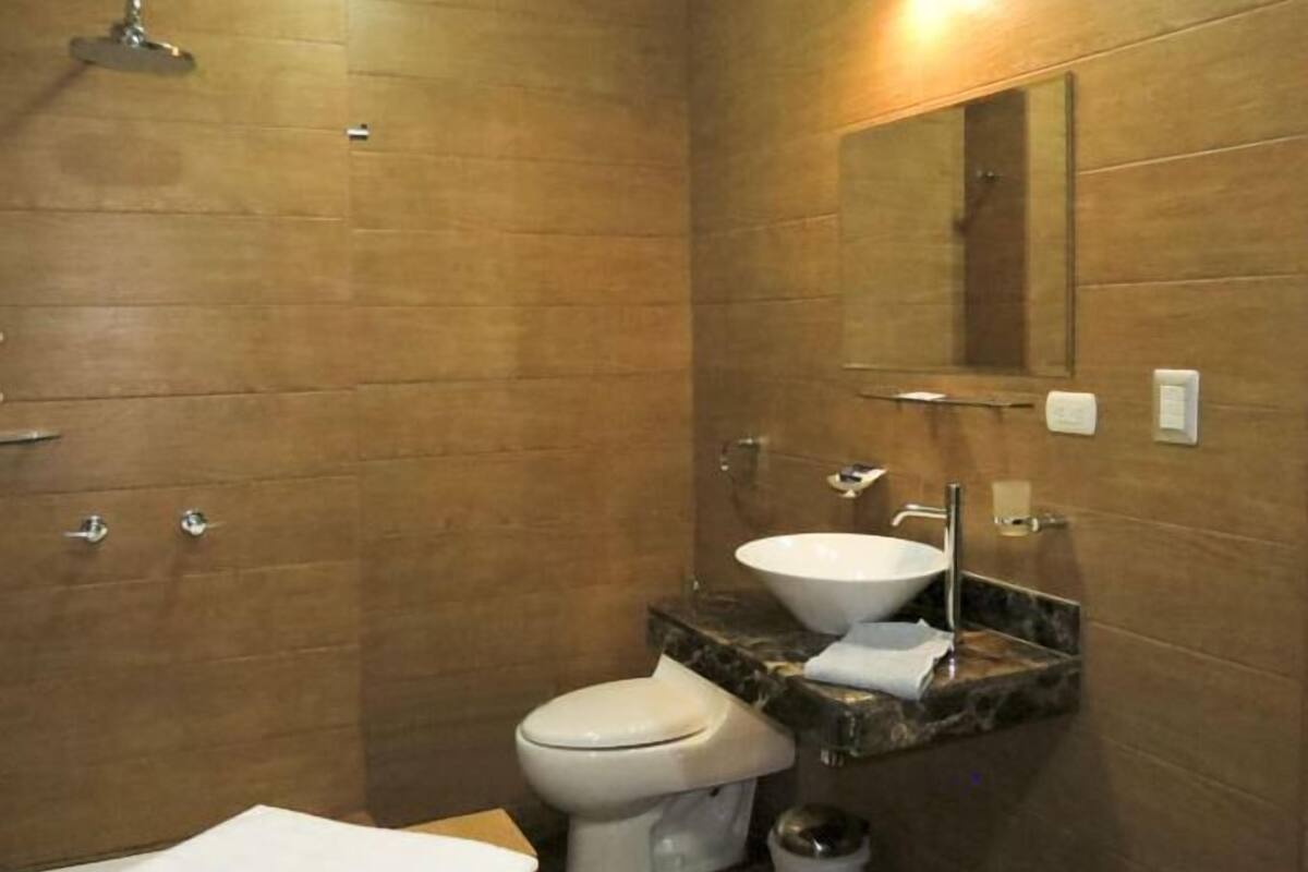 A bathroom with a toilet, sink, and mirror.
