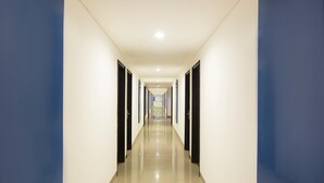 A long, narrow hallway with white walls and blue accents, leading to a series of doors. - Hotel Amaris Kuta - Bali (Legian)
