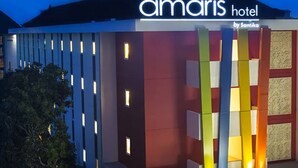 The exterior of the Amaris Hotel with a modern design, featuring a prominent sign and vertical light panels. - Hotel Amaris Kuta - Bali (Legian)