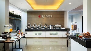 A modern breakfast bar with a branded sign, buffet setup, and dining area. - Hotel Amaris Kuta - Bali (Legian)
