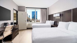 A hotel room with a large bed, a desk with a chair, a flat-screen TV, and a city view through the window.