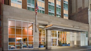 A hotel entrance with large windows, an American flag, and a sign reading "Hampton Inn."