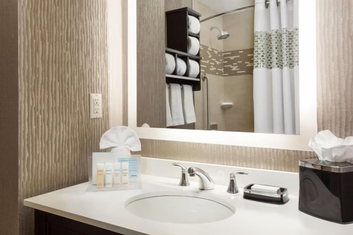 Casa de banho moderna com um espelho grande, uma sanita e suporte para toalhas, e uma caixa de lenços de papel.